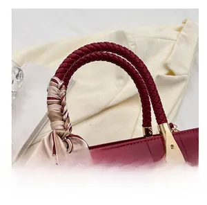 Detail of burgundy crocodile texture handbag featuring woven handle and striped silk scarf