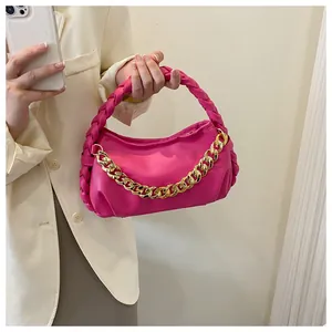 Detail of bright pink handbag with woven handle and decorative gold chunky metal chain