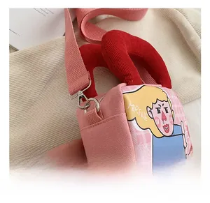 Detail of pink canvas crossbody bag showing a silver metal hook and red woven strap