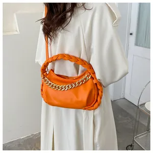 Detail of orange moon bag featuring woven top handle and chunky gold metal chain link