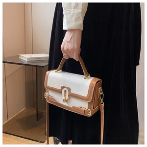 Dettaglio della borsa bianca con goffratura coccodrillo, finiture marroni e metallo oro