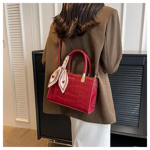 Detail view of red crocodile pattern shoulder bag with silk scarf on a model's shoulder