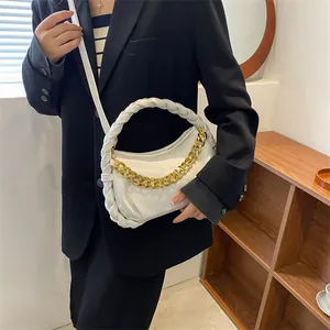 White pleated leather handbag with woven handle and gold chain strap worn by a model