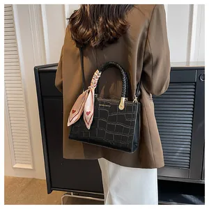Detail of black crocodile texture handbag with pink heart silk scarf and golden hardware