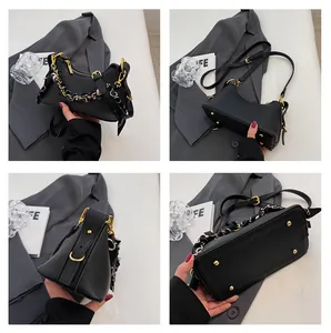 Detail view of black pebble leather handbag with gold hardware and silk scarf accent