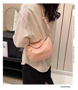 Close-up of salmon pink lychee leather handbag with a unique twisted braided shoulder strap