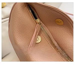Close-up of golden zipper and magnetic closure on textured litchi leather bag