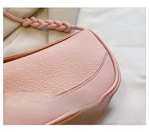 Detail shot of pink shoulder bag featuring lychee grain texture and woven strap