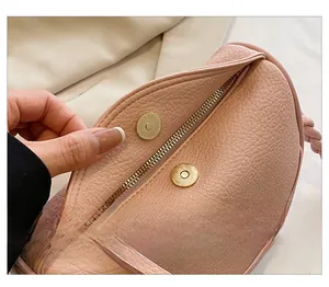 Close-up of pink lychee grain leather bag featuring secure gold magnetic snap and zipper