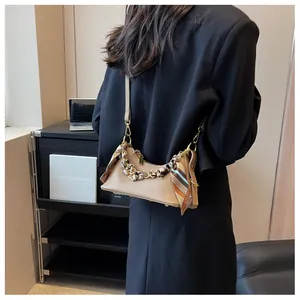 Detail of khaki hobo bag with gold chain and silk scarf on a model back