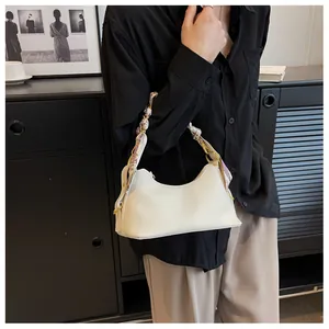White pebbled leather hobo bag with floral silk scarf detail worn by a model