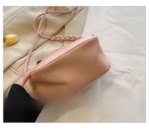 Detail shot of pink shoulder bag base with lychee texture and woven strap design
