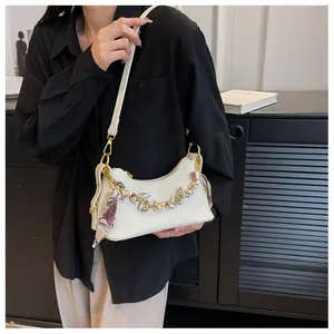 Close-up of white lychee leather handbag with decorative scarf and metal chain details
