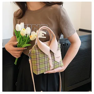 Detail view of plaid handbag with creative shirt collar design and pink leather handle