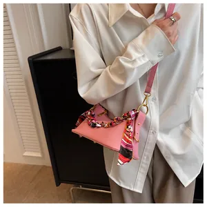 Detailed view of pink pebble leather crossbody bag with decorative floral silk scarf accessory