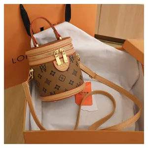 Macro detail of monogram cylinder bucket bag with gold hardware inside branded orange gift box