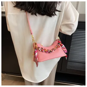 Detail view of pink lychee leather crossbody bag with silk scarf on gold chain strap