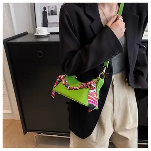 Detail of green pebble leather handbag with silk scarf wrapped on the chain handle
