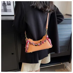 Detail of light brown lychee grain leather crossbody bag with a floral silk scarf handle