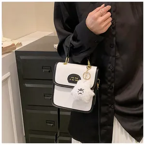 Dettaglio di una borsa a tracolla a contrasto bianco e nero con ciondolo a stella e logo