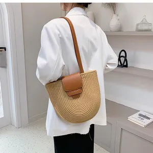Detailed side view of handmade straw bucket bag with brown leather strap and trim