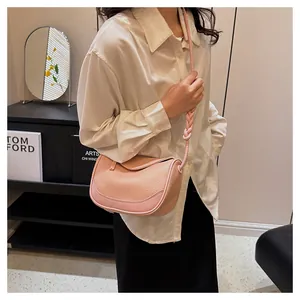 Detail of pink textured leather crossbody bag featuring a unique braided knot shoulder strap