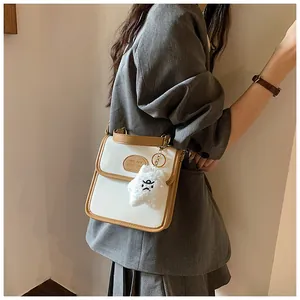 Dettaglio della borsa a tracolla beige e marrone con un ciondolo a stella in peluche su modella