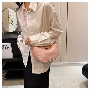 Detailed side view of pink pebbled leather shoulder bag on model showing size and scale