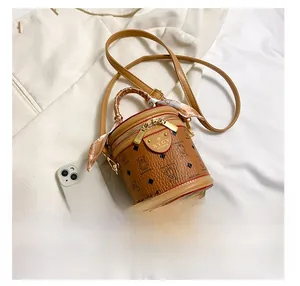 Detail of brown cylinder bucket bag with bear print, silk scarf handle and metal logo