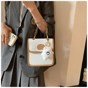 Dettaglio borsa vintage bianca con profili marroni e ciondolo a stella in peluche
