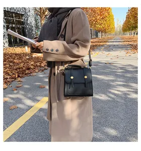 Close-up of black retro textured leather handbag with gold metal buckles and top handle