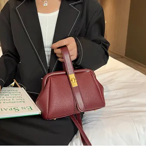 Détail d'un sac à main bordeaux en cuir grainé avec fermoir rotatif doré et bandoulière