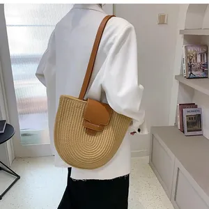 Detail of woven straw bucket bag with brown leather strap and elegant spiral texture