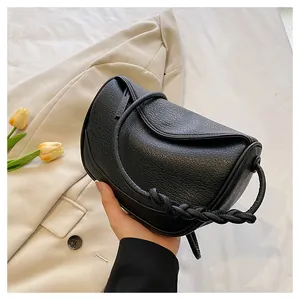Minimalist black lychee leather crossbody bag with woven handle detail shown from top view