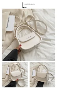 Detail of white faux leather crossbody bag with top handle and gold-tone hardware
