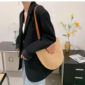 Detailed straw weave pattern of the semicircular bucket bag with brown leather accents