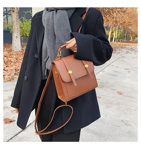 Close-up of brown faux leather crossbody bag with vintage gold buckles in autumn setting