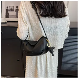 Detail of black lychee grain leather dumpling bag with cute elephant charm on a model