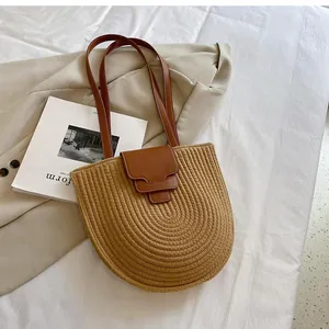 Detail of half-moon straw bucket bag with layered leather flap and long handles