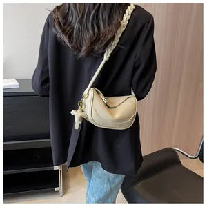 Detail showing beige moon bag with woven strap and elephant charm on casual model outfit