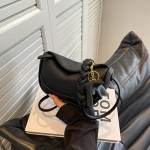 Minimalist black pebble leather dumpling bag with woven handle and leaf pendant