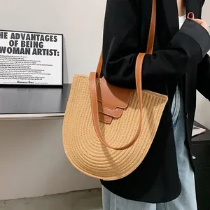 Minimalist straw bucket shoulder bag featuring woven texture and brown leather flap