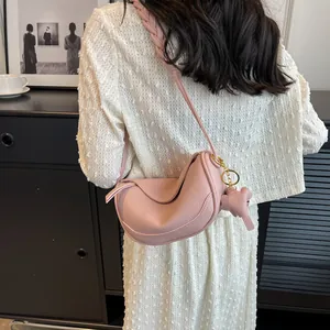 Pink crescent shoulder bag in lychee pattern leather with a woven strap and horse charm