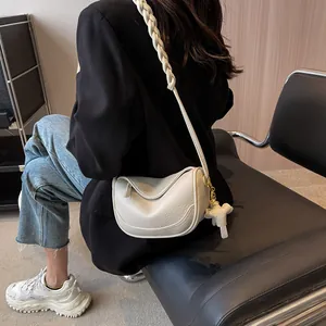 Chic cream pebble leather crossbody dumpling bag with woven strap and elephant charm