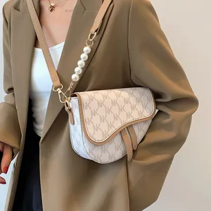 Klassieke zadeltas van monogramleer met elegante parelaccenten en bruine randafwerking