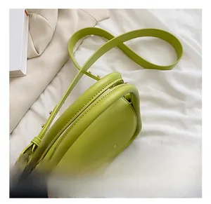 Detail view of avocado green leather bag with slim handles and golden hardware accents