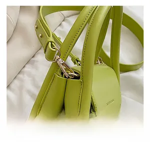 Close-up of premium light green leather handbag with gold metal swivel hook details