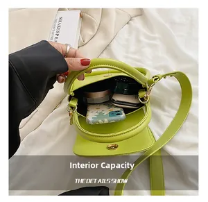 Internal capacity of green leather small square bag showing phone and lipstick storage