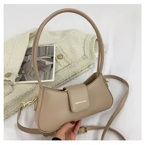Nahaufnahme der beigen Halbmond-Tasche mit goldenen Details und Schriftzug