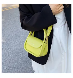Outdoor street style shot of a neon green mini crossbody bag with FASHION & BAGS logo